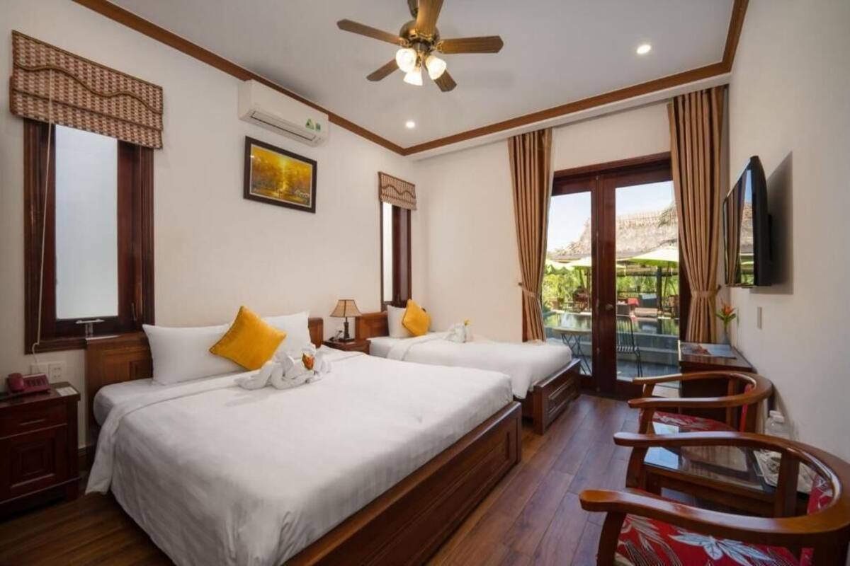 Hotelkamer met twee bedden, een plafondventilator, een televisie, een bureau en een balkon met uitzicht.
