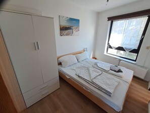 Een slaapkamer met een bed, een kledingkast, een raam met uitzicht en een schilderij aan de muur.