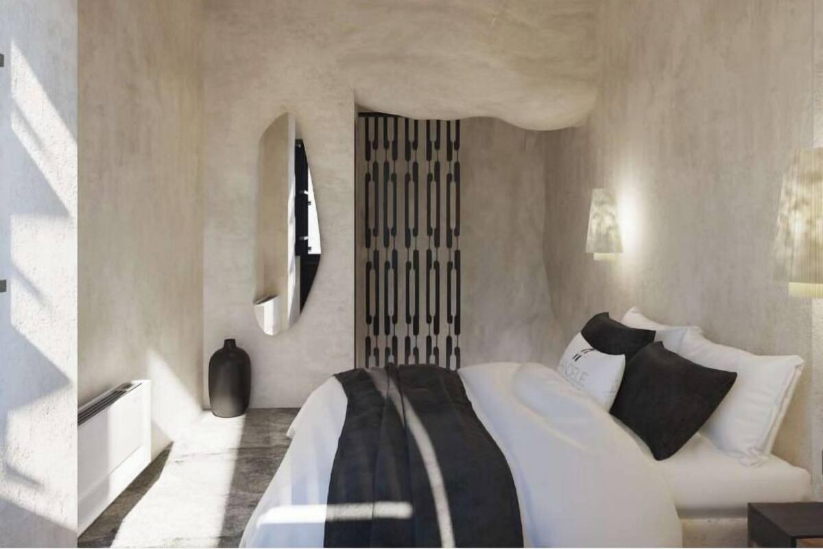 Une chambre à coucher moderne avec un lit, une couverture à rayures noires et blanches, un vase noir et un décor mural original.