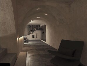 A modern interior with a stone archway leading to a kitchen area. - Anemos Central Fira (Santorini)