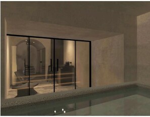 A modern interior with a glass partition, a pool, and a visible dining area. - Anemos Central Fira (Santorini)