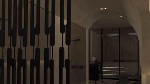 An interior corridor with a modern design, featuring a patterned wall and a seating area with a table and chairs. - Anemos Central Fira (Santorini)