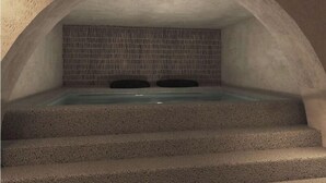 A stone-walled hot tub with steps leading up to it. - Anemos Central Fira (Santorini)
