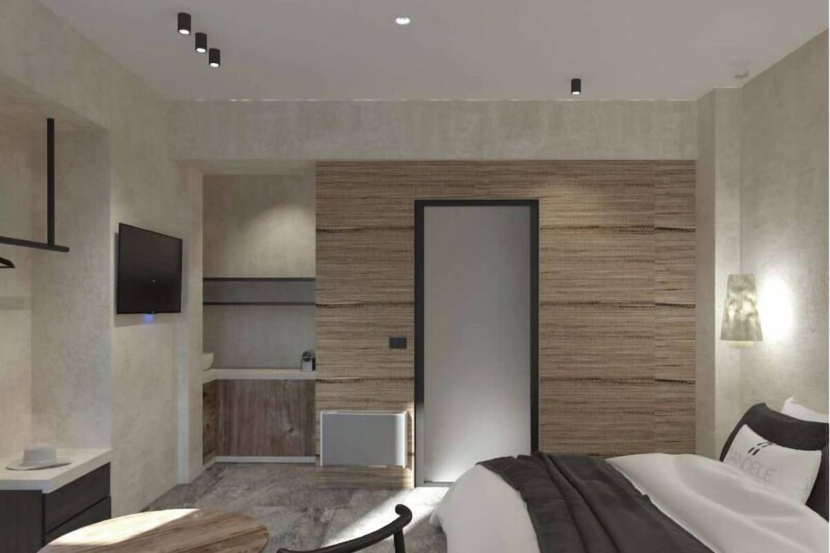 Une chambre d’hôtel moderne équipée d’un lit, d’un bureau, d’une chaise, d’une télévision et d’une salle de bain.