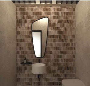 A bathroom with a textured wall, a modern mirror, a round sink, and a small shelf with a bottle. - Anemos Central Fira (Santorini)