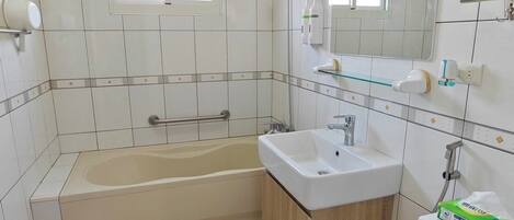 A bathroom with a bathtub, sink, toilet, and a window.