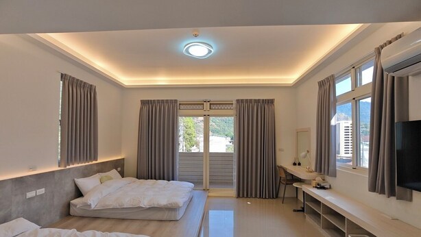Habitación de hotel con dos camas, un escritorio, televisión y vistas al exterior.