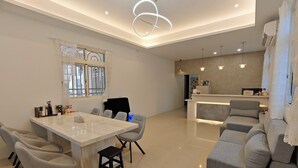 Una sala moderna con comedor, un sofá, una mesa de centro y una cocina al fondo.