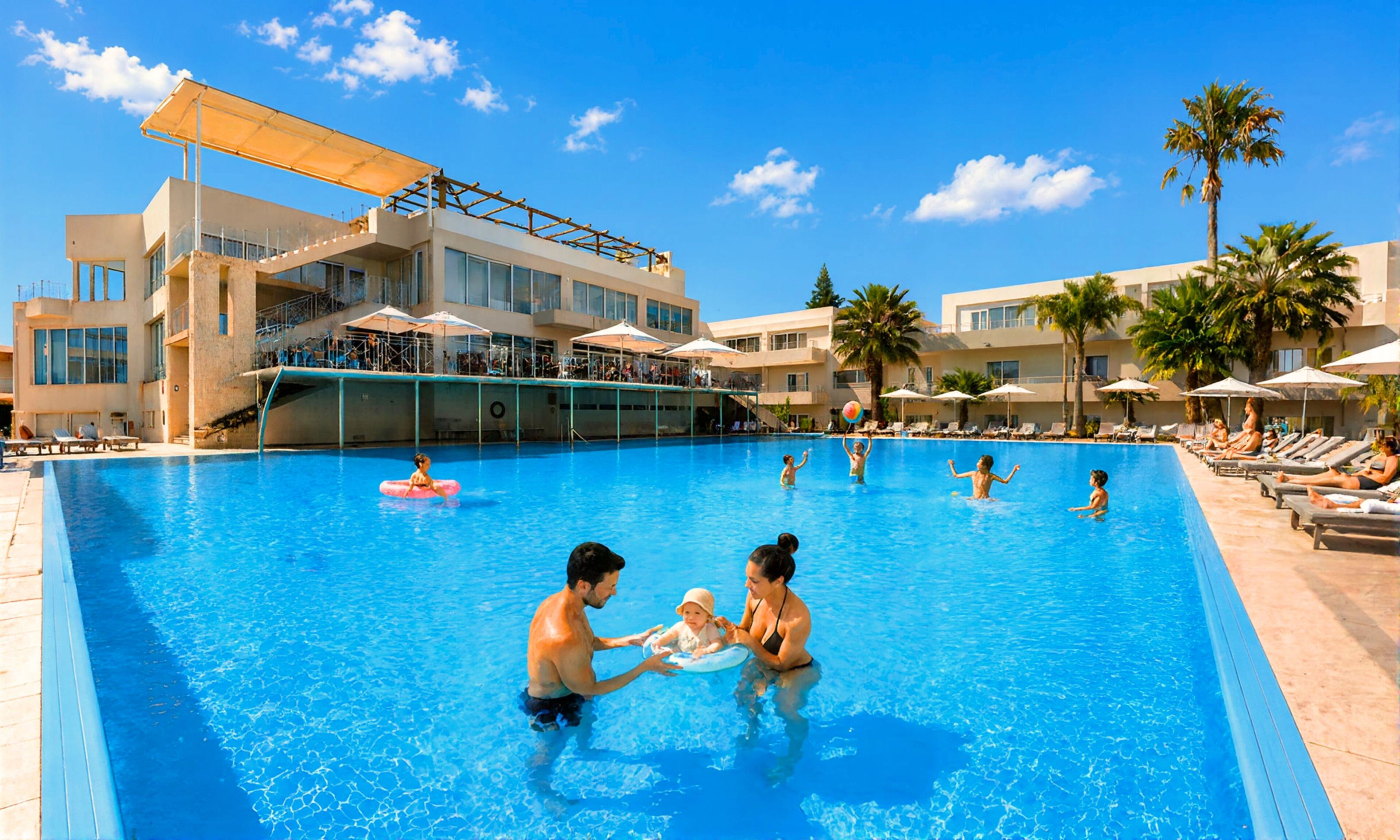 A swimming pool with a lifeguard stand, lounge chairs, and umbrellas.