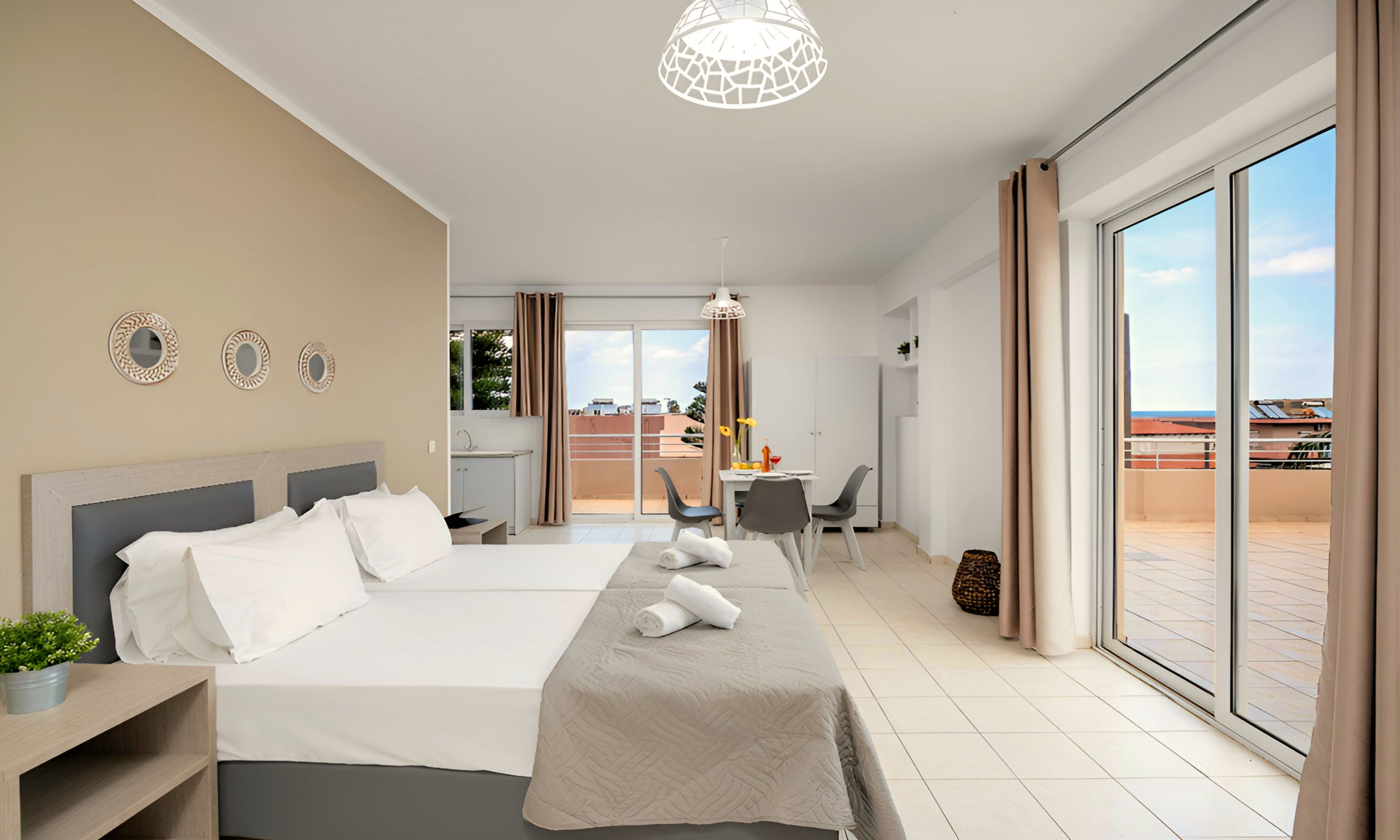 Een hotelkamer met een bed, een bureau, een stoel, een tafeltje, een potplant en uitzicht op buiten.