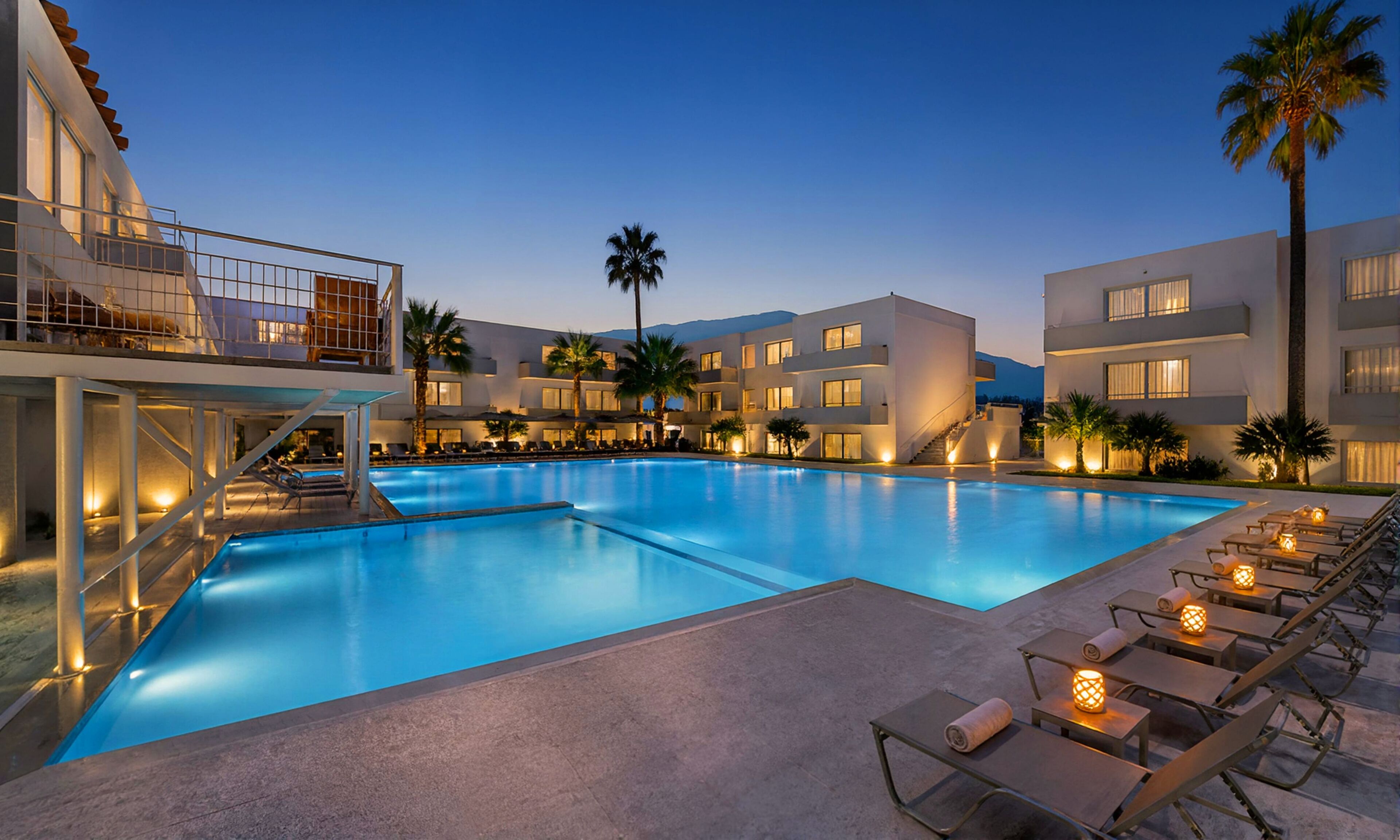 A hotel with a swimming pool, sun loungers, and a staircase leading to the upper floors.