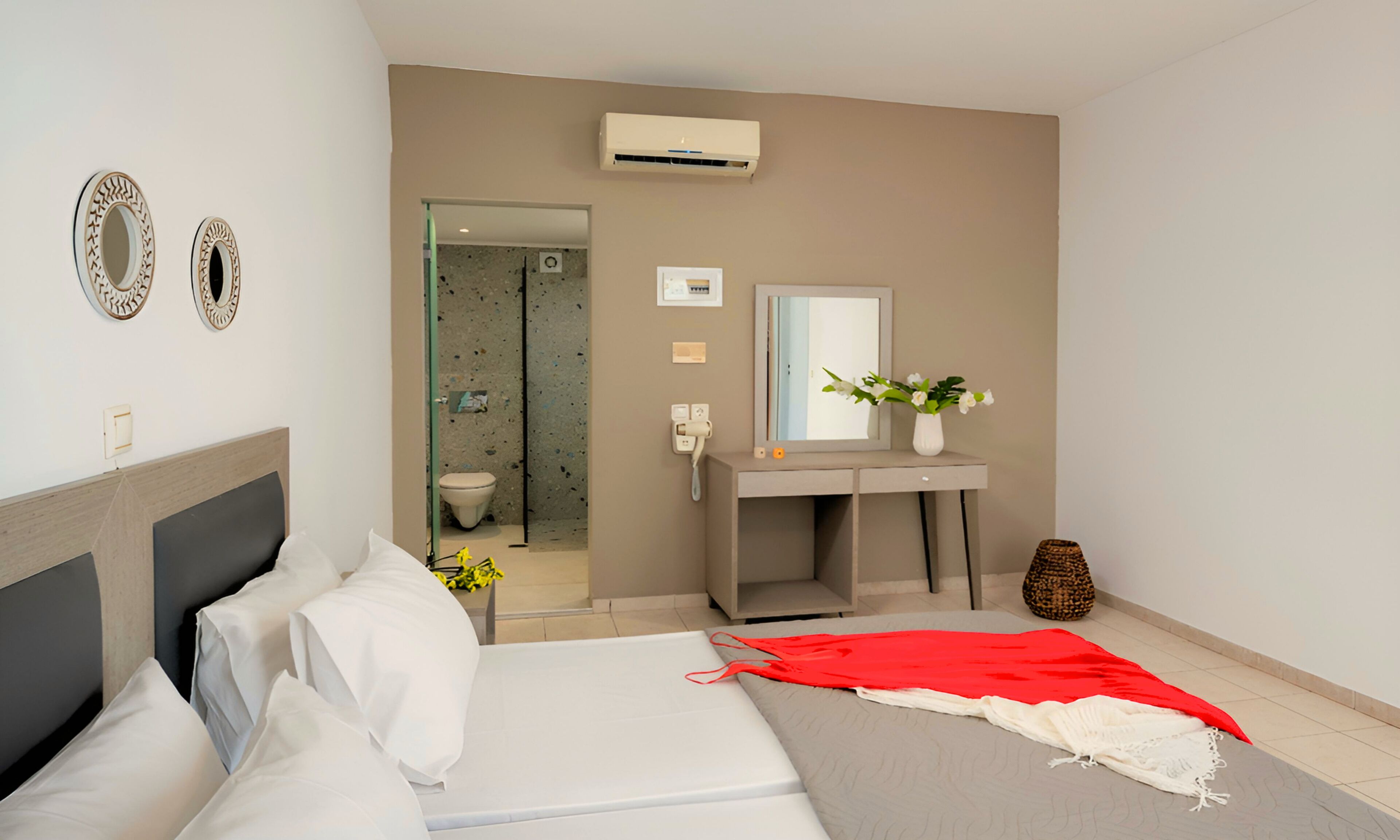 Een moderne hotelkamer met een bed, nachtkastje, spiegel en een badkamer die door een open deur zichtbaar is.