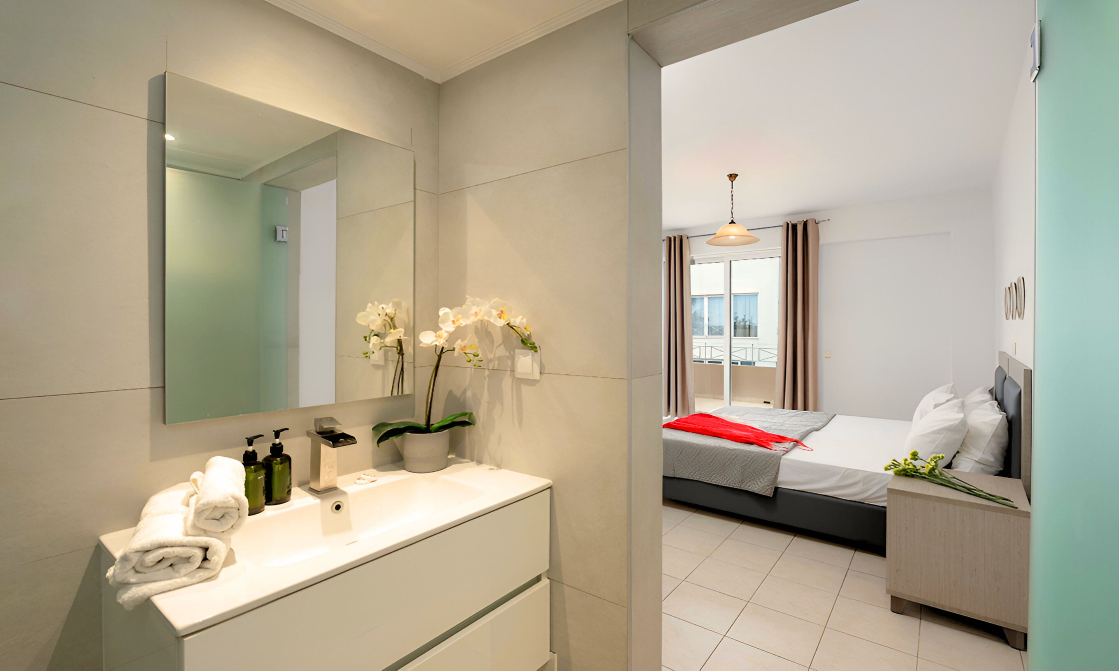 A modern bathroom with a large mirror, white sink, and two white towels.