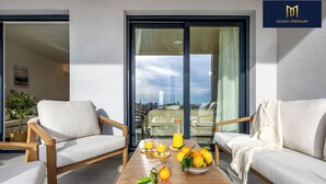 A modern balcony with a sofa, chairs, a table with fruit and drinks, and a city view. - Brisa Azul 2-bedroom apartment in punta prima, pool, gym, jacuzzi (Torrevieja)