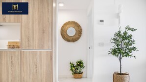 A modern interior with a wooden wardrobe, a round mirror, a potted plant, and a basket with flowers. - Brisa Azul 2-bedroom apartment in punta prima, pool, gym, jacuzzi (Torrevieja)