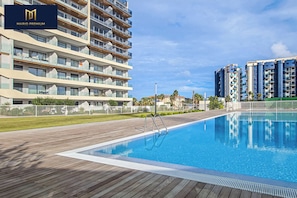 Ein modernes Hotel mit Schwimmbad, mehreren Balkonen und einem gepflegten Außenbereich.