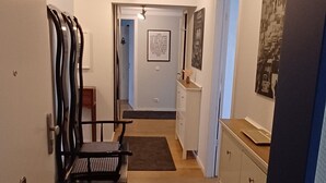 Een gang met een plafondventilator, een bank, een kast en een deur naar een andere kamer.