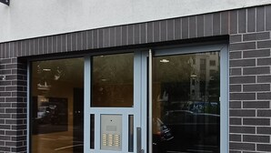 Een gebouw met een glazen deuropening, een codekluis en een klein raam boven de deur.