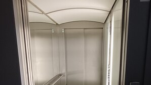 Een lift met metalen wanden, een handrail en een bordje met de tekst 'lift'.