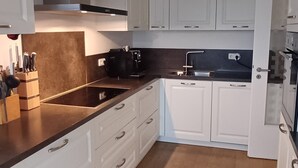 Een moderne keuken met witte kasten, een zwart aanrecht en een beige vloerkleed.
