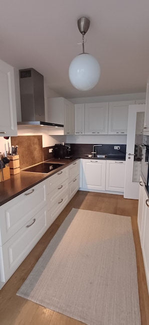 Una cocina moderna con armarios blancos, encimera negra y alfombra color beige.
