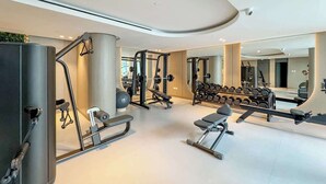 Een moderne sportschool met diverse trainingsapparaten, een grote spiegel en een ruimtelijke, schone indeling.