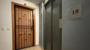 A hallway with a wooden door and an elevator. - Splendid apartment with sea view 50m from the beach with snack restaurant (Empuriabrava)