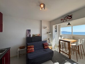 A bedroom with a bed, a desk, and a view of the sea.