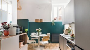 Uma cozinha moderna com área de jantar, piso de madeira e uma parede em tom de verde-água.