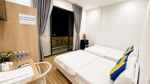 Habitación de hotel con cama, escritorio con artículos de aseo, silla y balcón con vistas.