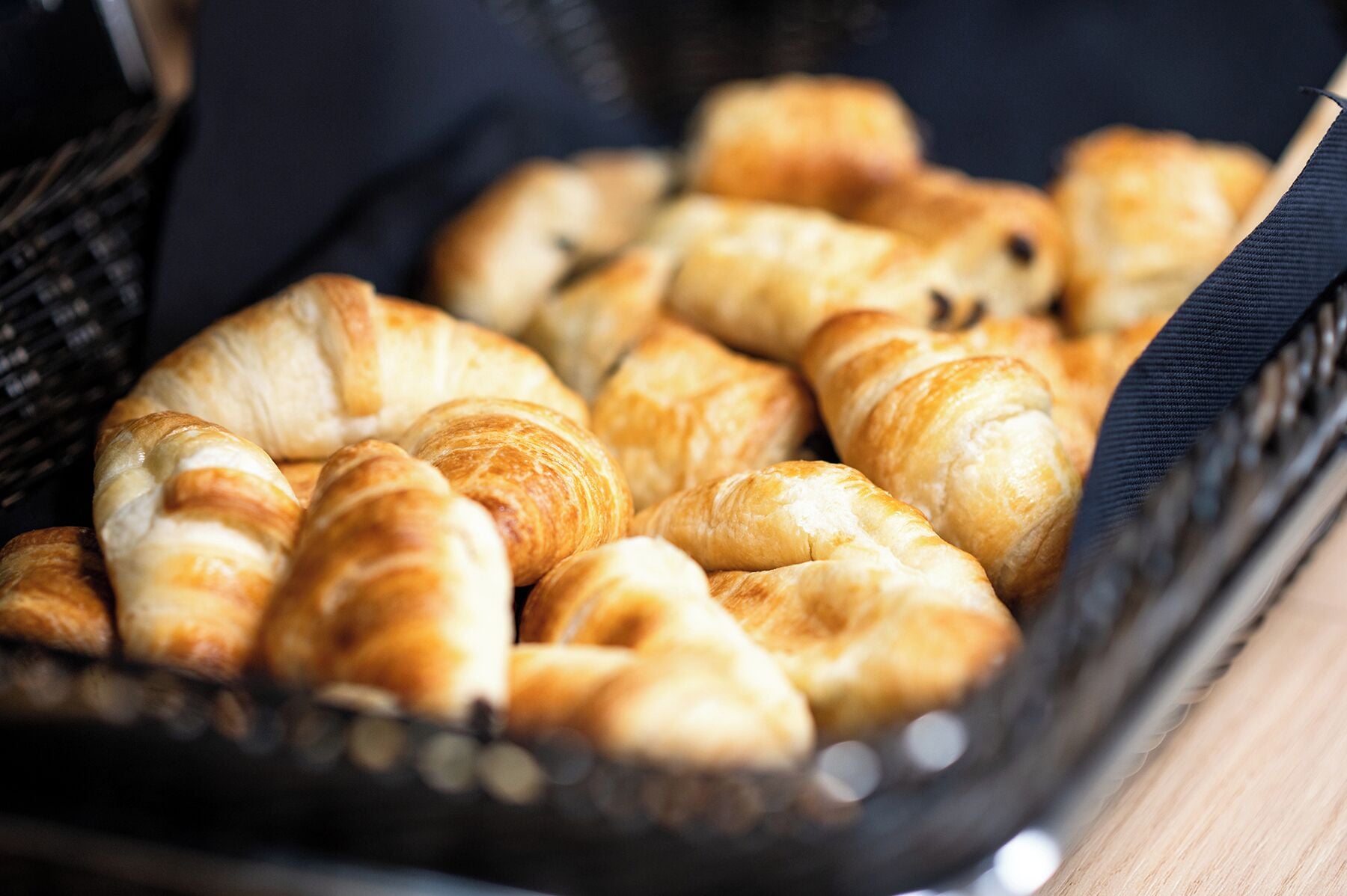 A basket filled with golden-brown croissants.