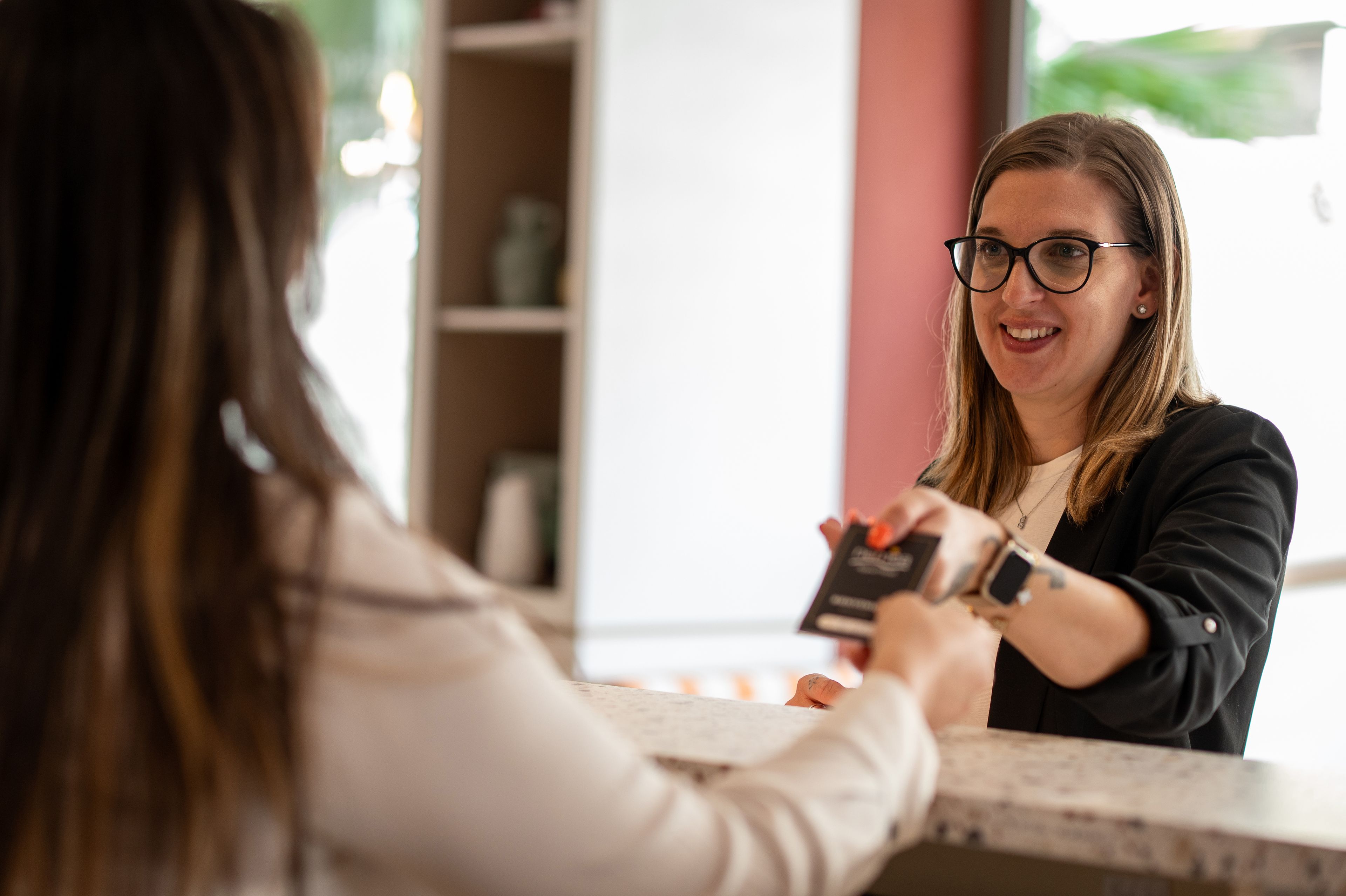 A person at a counter, possibly a hotel reception, with a blurred background suggesting indoor space.