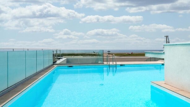 Una piscina en la azotea con vistas claras al océano.
