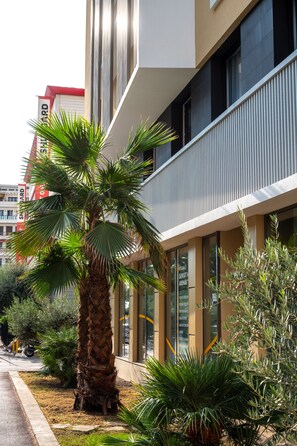 A modern building with a palm tree in the foreground, a balcony with vertical siding, and a sign indicating 'Sunset Arenas.' - Nemea Appart Hotel Nice Sunset Arenas (Nice)