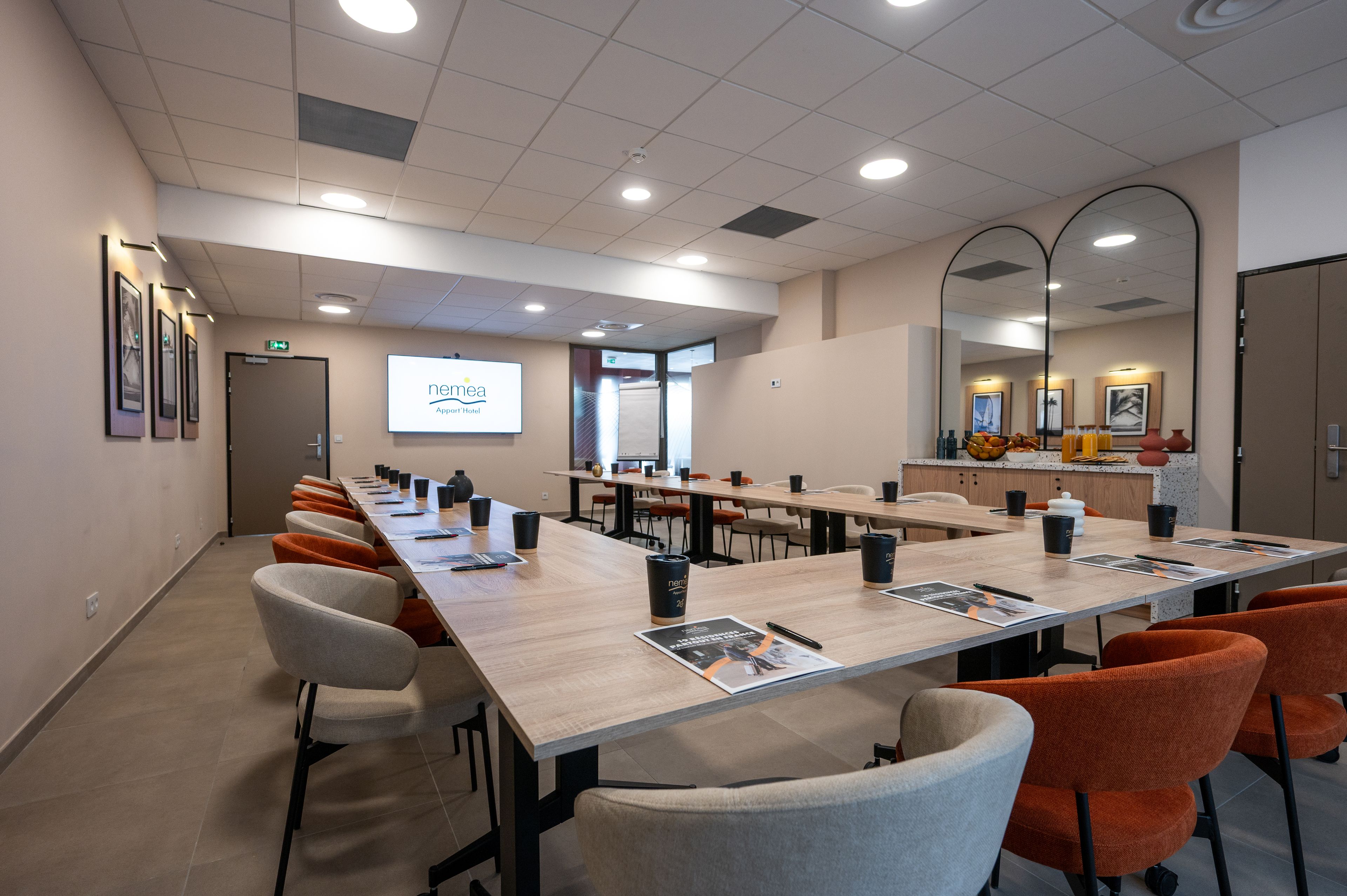 Ein Konferenzraum mit einem langen Tisch, Stühlen und einer Projektionsleinwand.