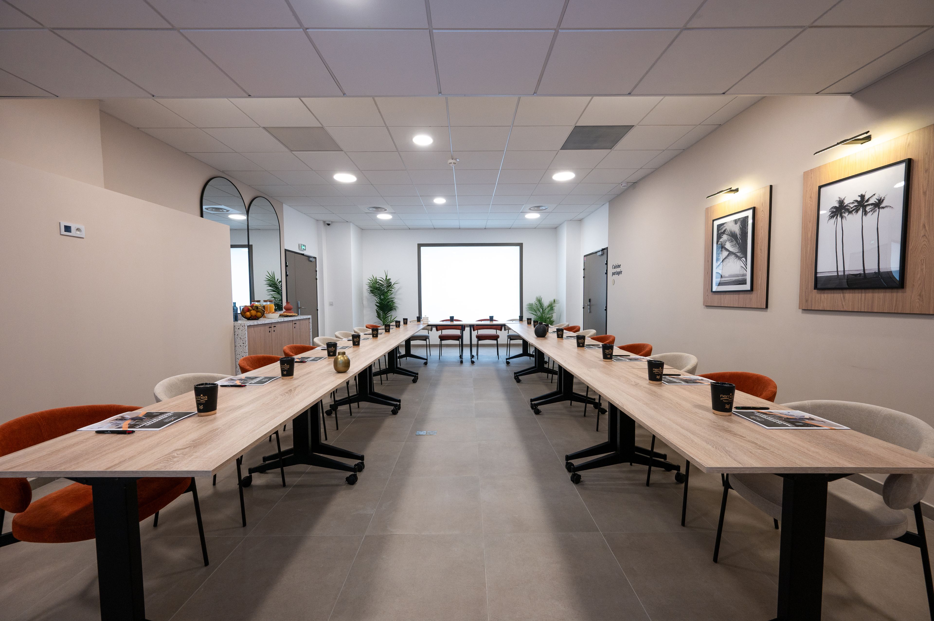 Une salle de conférence avec une longue table, des chaises et une grande fenêtre.