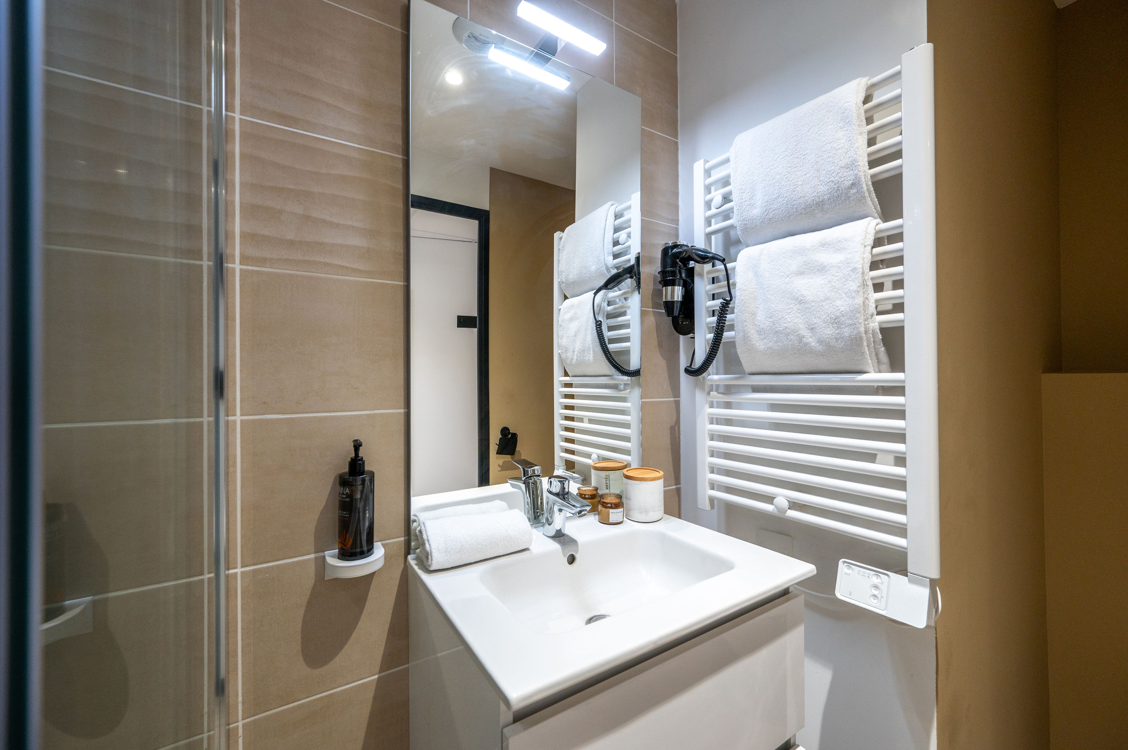 Een moderne badkamer met een wit wastafel, een spiegel en twee handdoekrekken.
