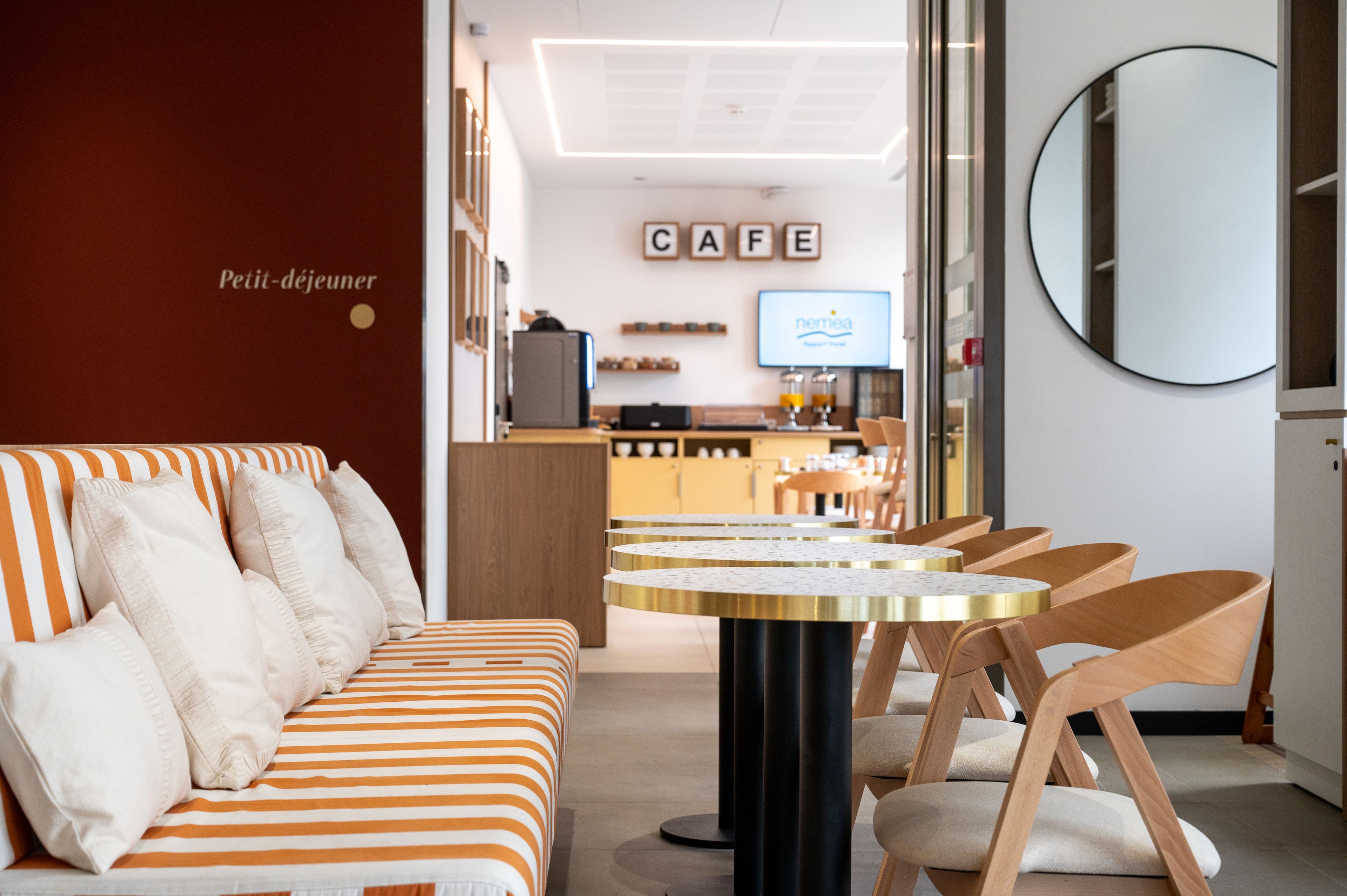 Un intérieur moderne avec un canapé à rayures, une table ronde et des chaises en bois.