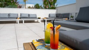 Una terraza en la azotea con sillones de descanso, una mesa con bebidas y cielo despejado.