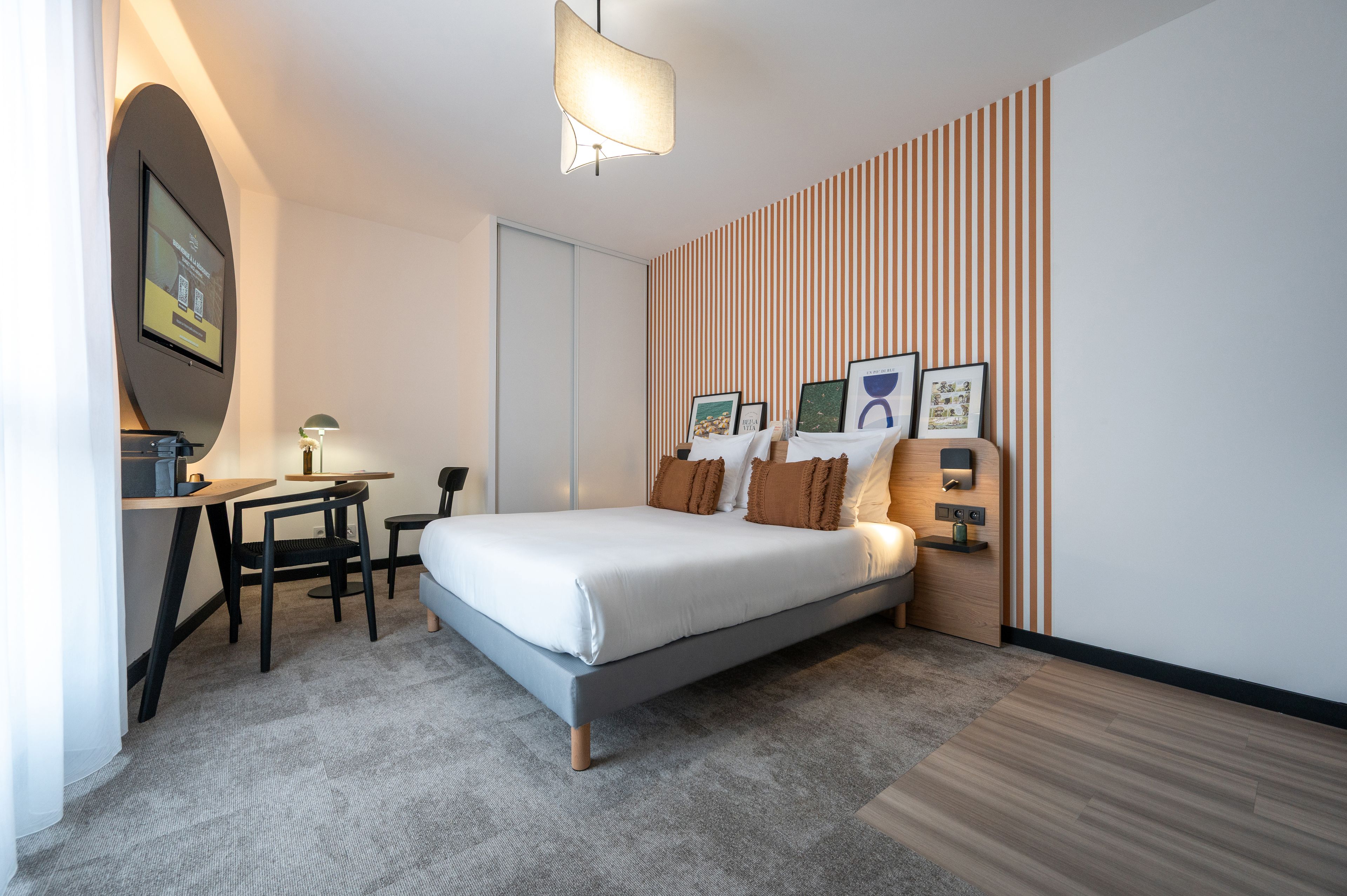 A modern hotel room with a bed, desk, and seating area.