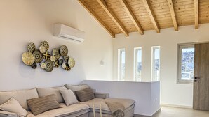 Una sala de estar moderna con un sofá modular, decoración en la pared, un ventilador de techo y ventanas amplias.