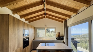 Una cocina moderna con vigas de madera, un ventanal y vistas al paisaje.