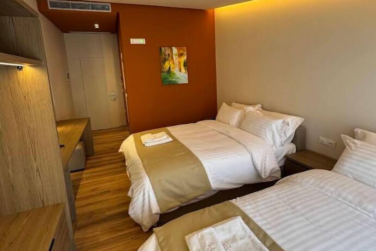 Habitación de hotel con dos camas, piso de madera, un cuadro en la pared y una puerta.