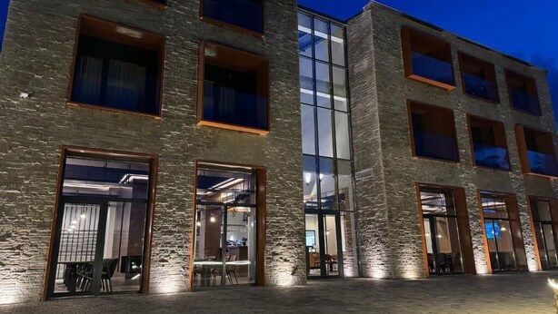 Un immeuble à plusieurs étages, doté de grandes fenêtres et d’une façade en briques.