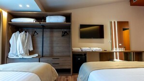 Une chambre d’hôtel avec deux lits, une armoire, une télévision et un minibar.