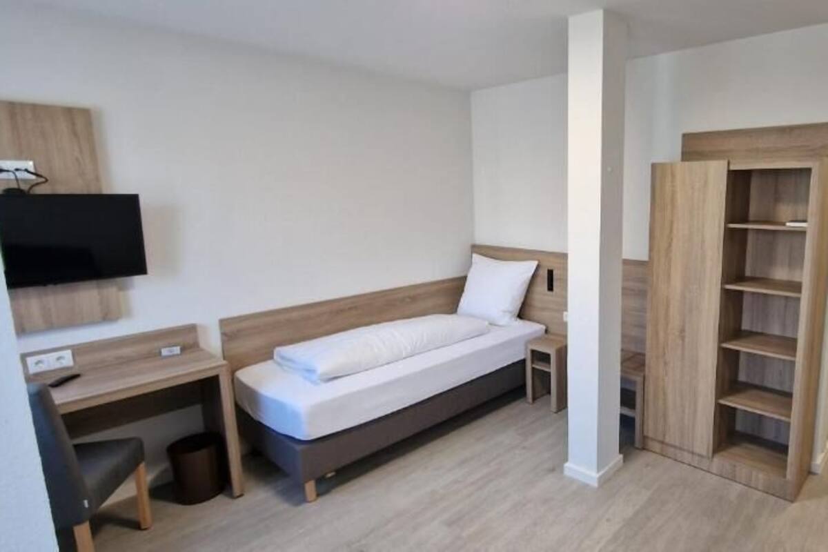Un dormitorio con cama, escritorio, televisor y armario.