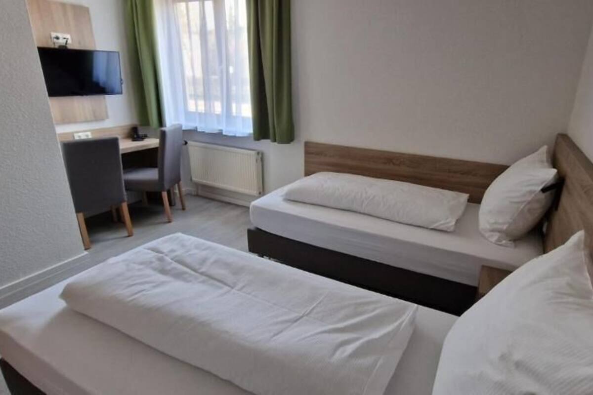 Una habitación de hotel con dos camas, un escritorio, una silla y un televisor.