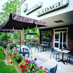 A hotel patio with outdoor seating, a brick facade, and a sign reading 'HOTEL LADAGE.' - Hotel Ladage (Frankfurt)