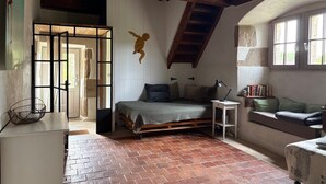 Une chambre à coucher rustique avec un espace de couchage en mezzanine, une petite table de chevet et une fenêtre donnant sur un beau paysage.