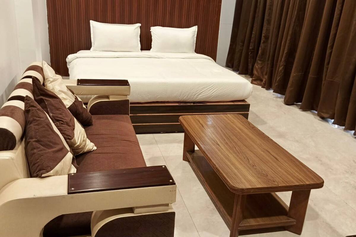 Quarto com cama, sofá e mesa de madeira.
